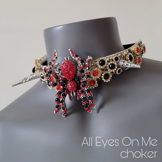 Halsband I silverfärgad metall med spikes och en stor röd och svart spindel av glas kristall som knyts runt halsen.