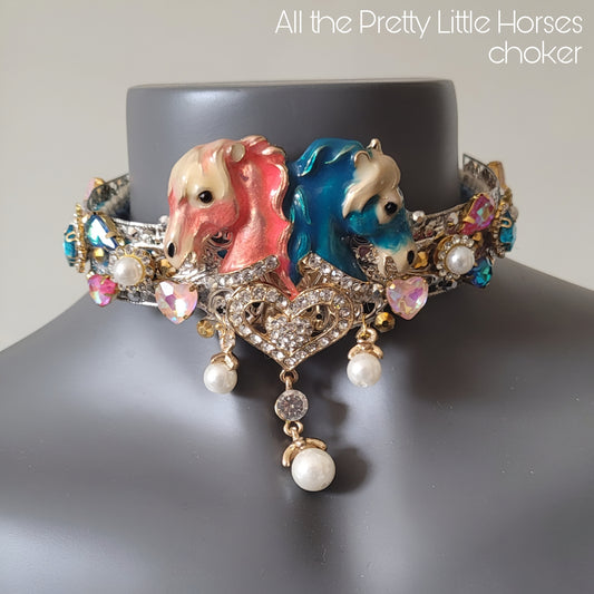 WhatEver collection: The All The Pretty Little Horses metal choker with two horse heads (pink and blue), dangling pearls, high quality glass crystals, rhinestones, and two coloured velvet ribbons