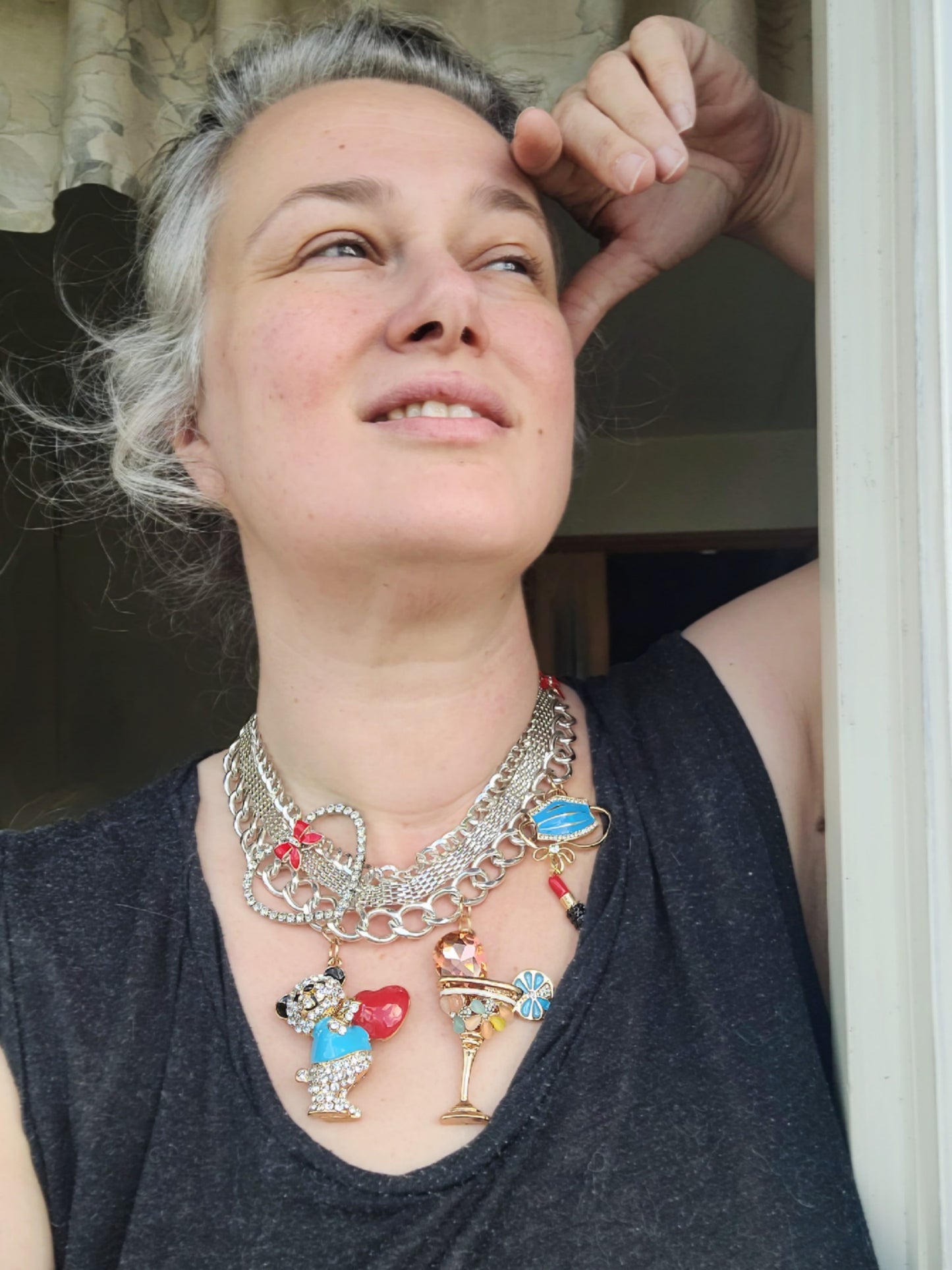 WhatEver collection: The Home Party metal necklace in silver coloured metal adorned with a crystal heart, red ribbons, and various crystal encrusted pendants including a face mask, lipstick, bear holding a heart, and a drink